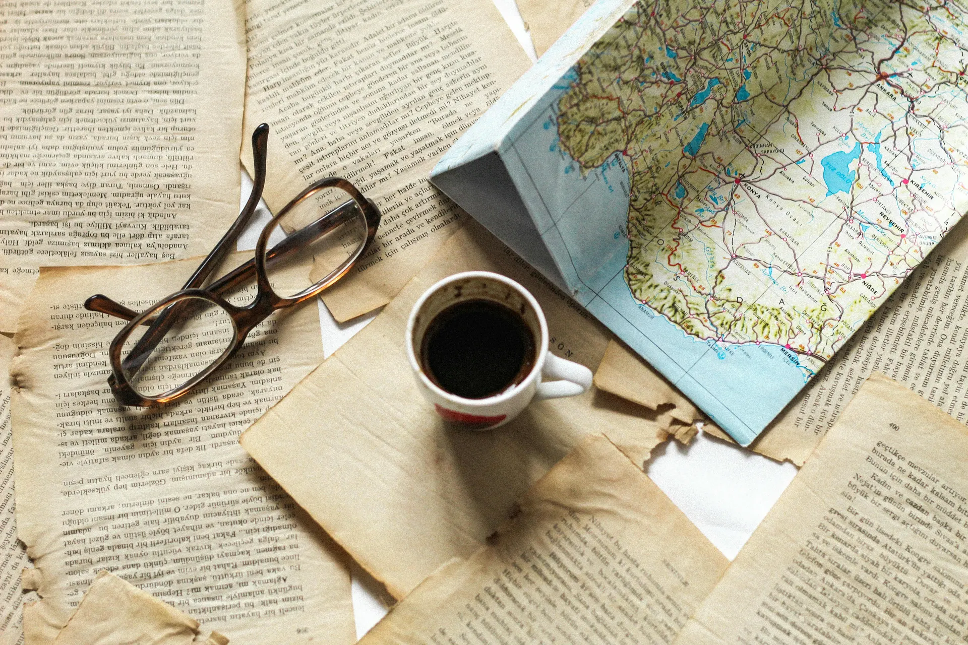 Passport, sunglasses, tickets and map on a warm beige travel desk