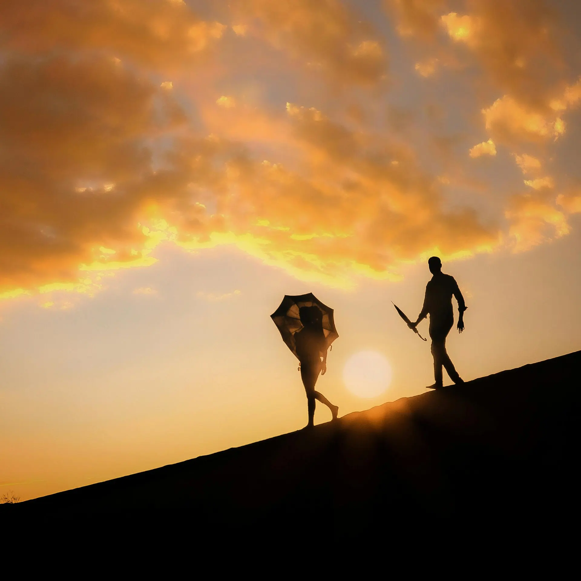 Travellers walking across dunes toward a luxury desert camp at sunset
