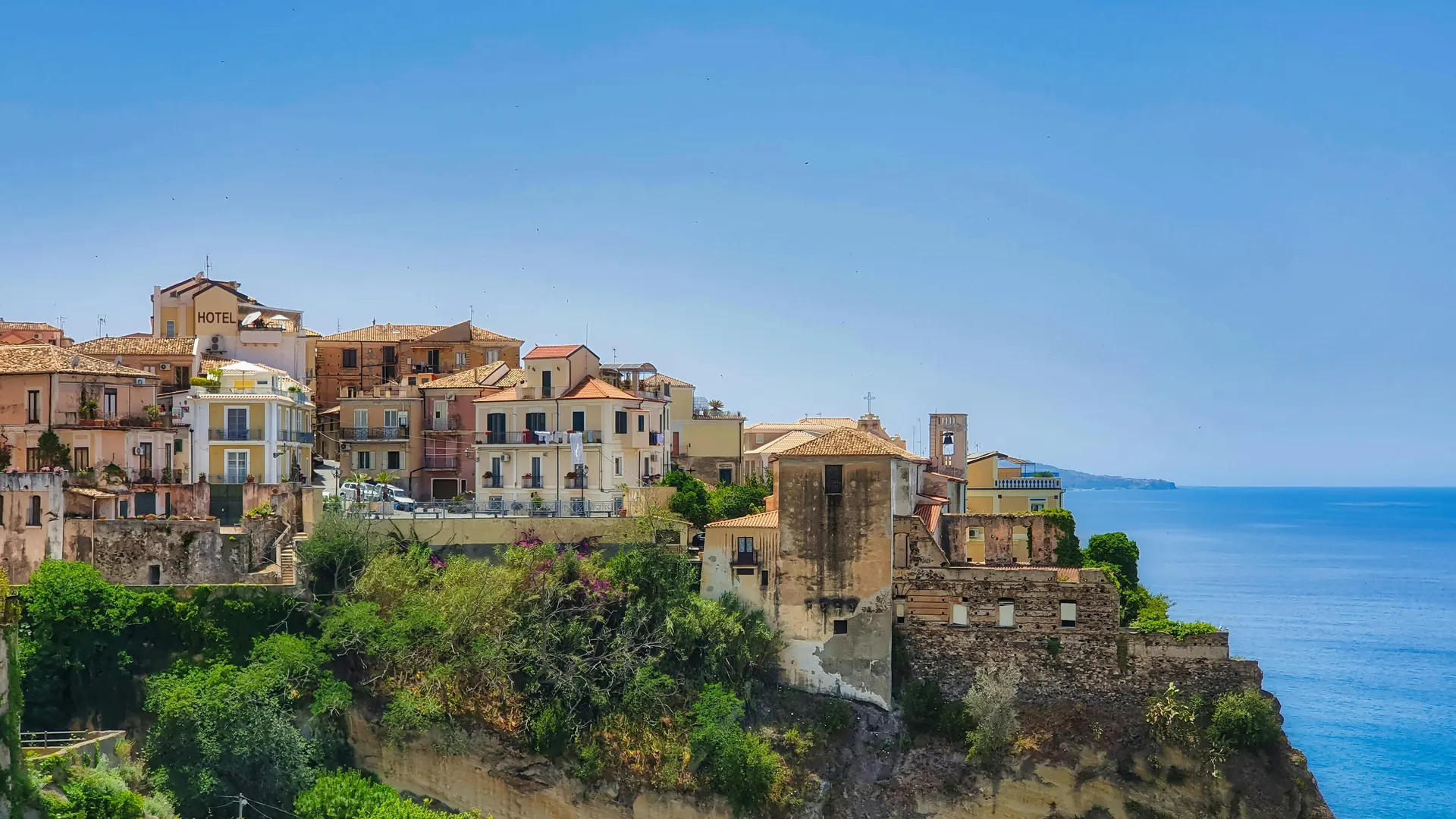 Sunlit coastline with azure sea and terracotta architecture in a premium travel mood